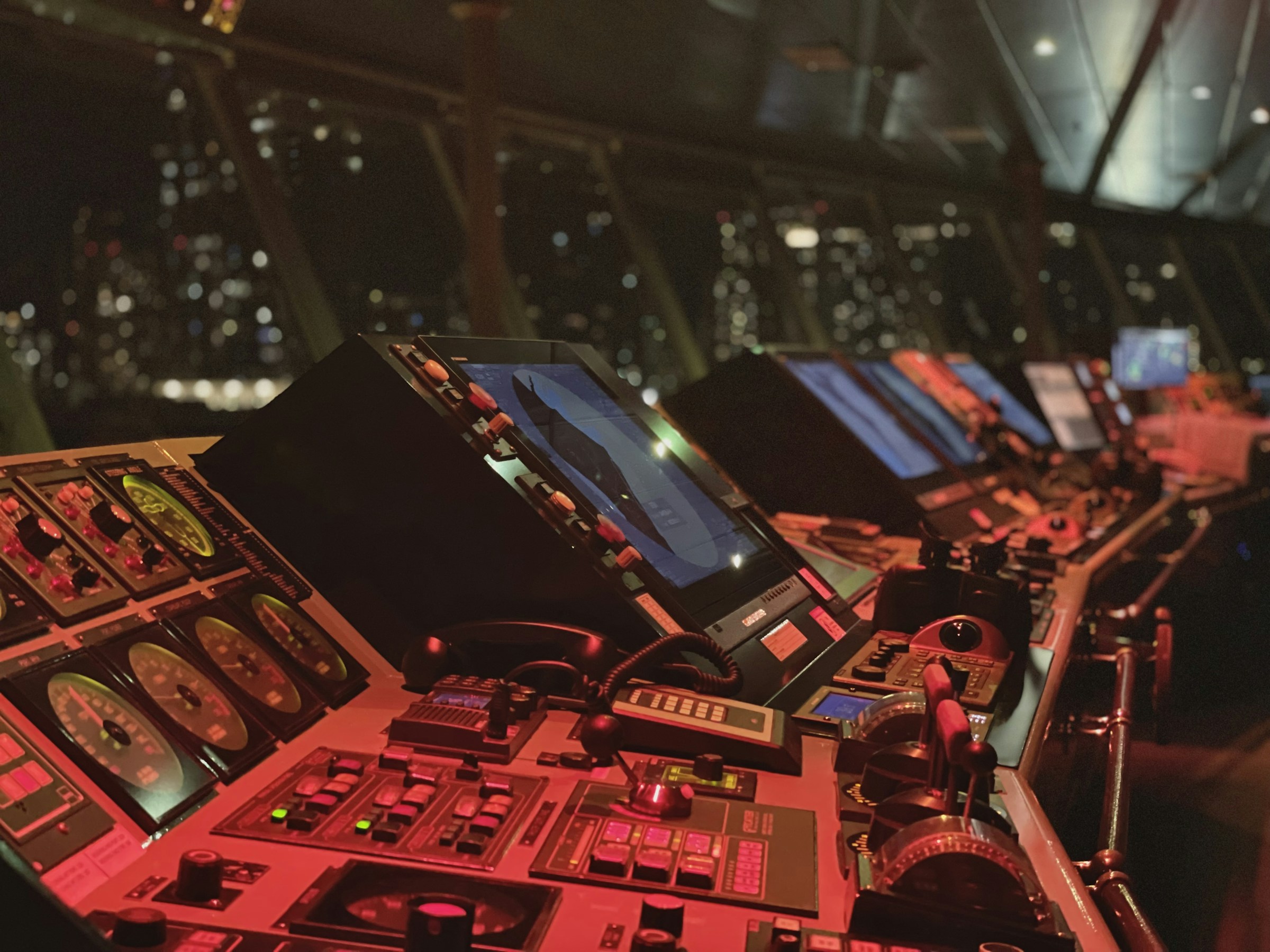 Vessel bridge console at night with glowing radar and navigation screens